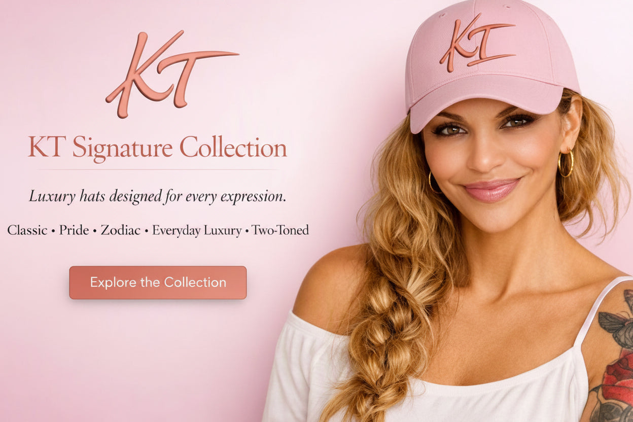 A woman wearing a light pink KT Signature Collection baseball cap and a white off-the-shoulder top, posed against a soft pink background with brand text and an 'Explore the Collection' button.
